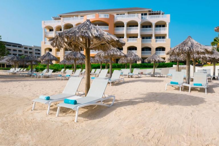 Tumbonas con sombrillas de palma en la playa del Iberostar Selection Rose Hall Suites All Inclusive Jamaica