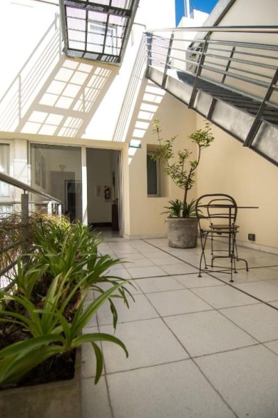 Terraza interior con plantas y mobiliario de hierro forjado en Magnolia Hotel Boutique