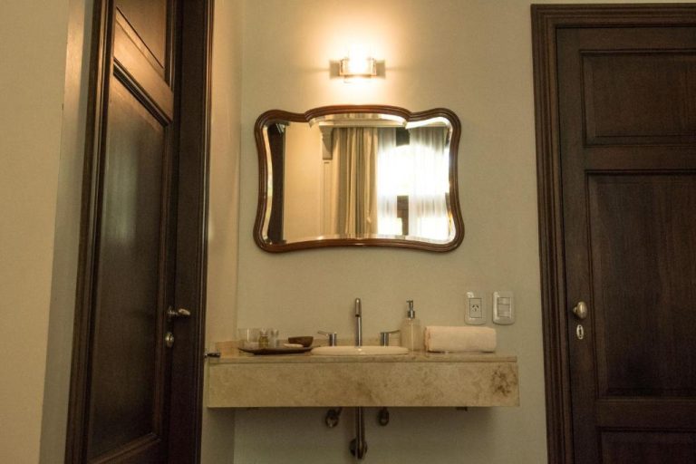 Baño elegante con lavabo de mármol y espejo vintage en Magnolia Hotel Boutique