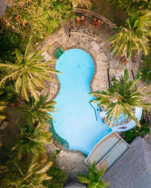 Vista aérea de la piscina tropical del Severin Sea Lodge rodeada de palmeras y piedra natural