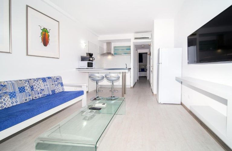 Salón con sofá azul y cocina americana integrada en Apartamentos Monte Verde