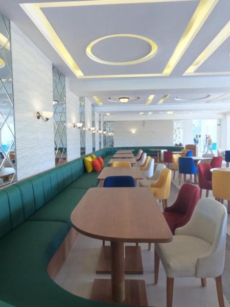 Restaurante interior del Hacienda Samana Bay Hotel con sofás verdes y sillas de colores vibrantes