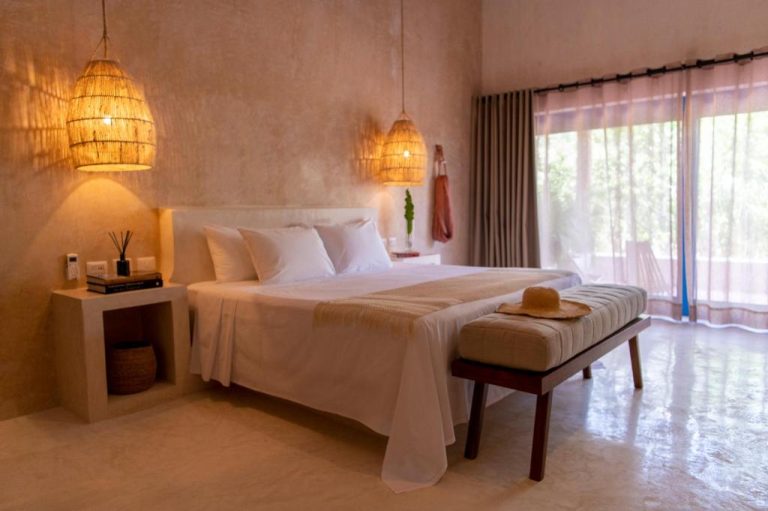 Habitación de lujo con cama king, lámparas de mimbre y ambiente cálido en Wakax Hacienda Boutique Hotel
