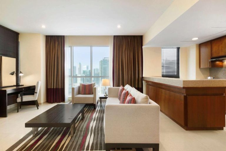 Salón amplio con cocina americana y vistas al skyline del Ramada by Wyndham Downtown Dubai