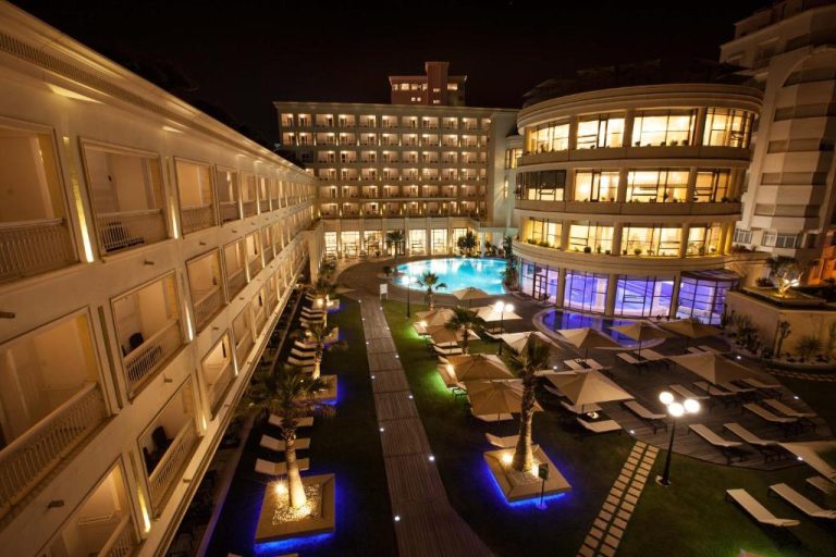 Vista nocturna de la piscina exterior y jardines iluminados del Sousse Palace Hotel & Spa