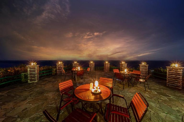 Terraza exterior nocturna con mesas iluminadas y vistas al océano en PrideInn Flamingo Beach Resort Mombasa