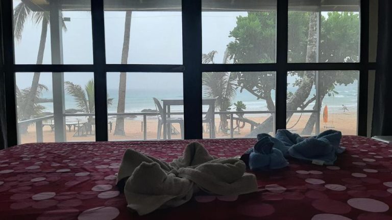 Habitación con vista panorámica a la playa y palmeras desde la cama en Duli Beach Resort