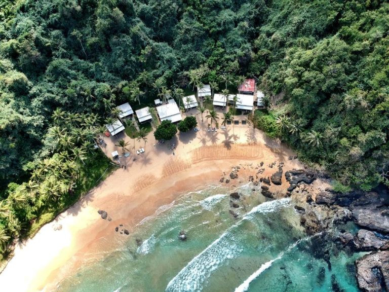 Vista aérea del Duli Beach Resort con cabañas frente a la playa rodeadas de selva tropical