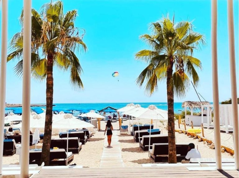 Playa privada con hamacas, sombrillas blancas y palmeras del So Nice Beach Resort junto al mar
