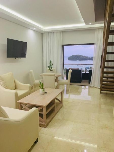 Sala de estar con sofás blancos y vista panorámica al mar en Hacienda Samana Bay Hotel