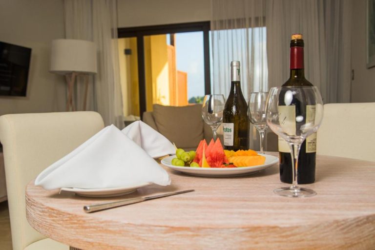 Mesa con botellas de vino, copas y plato de frutas frescas en Hacienda Samana Bay Hotel