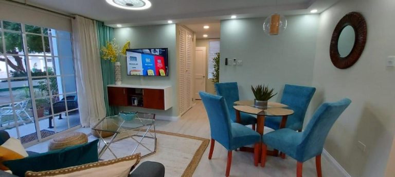 Sala de estar y comedor moderno con sillas azules y TV en Almond Grove at Sand Castle