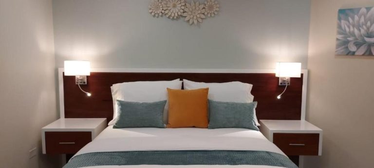 Habitación doble de lujo con cama king size y cabecero de madera en Almond Grove at Sand Castle