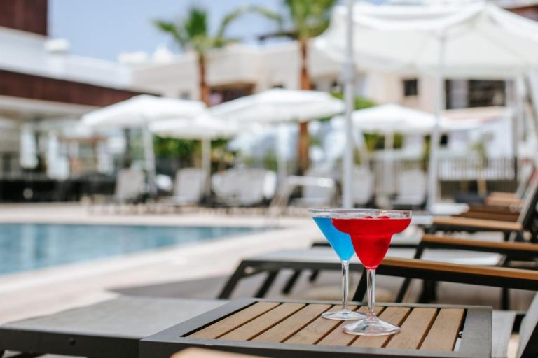 Cócteles coloridos junto a la piscina exterior con tumbonas y sombrillas del Cosmo Napa Boutique Hotel