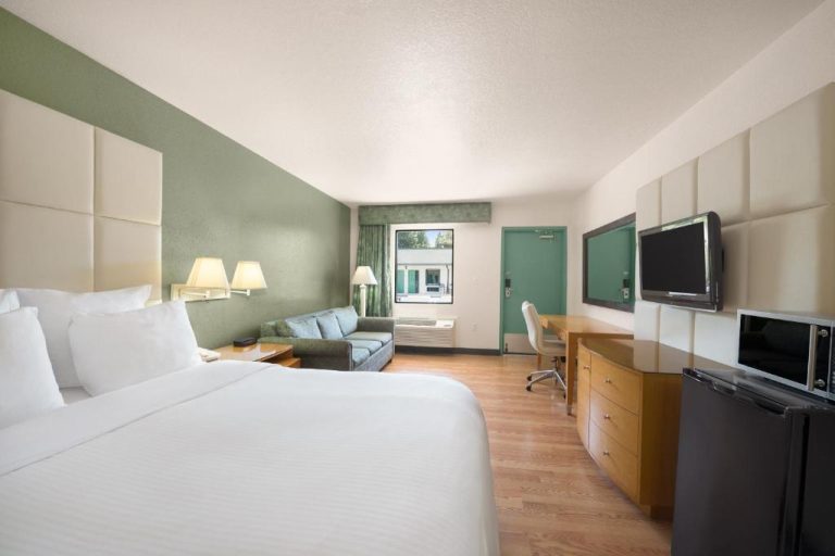 Habitación king size con sofá, escritorio y TV en Travelodge by Wyndham Florida City Everglades