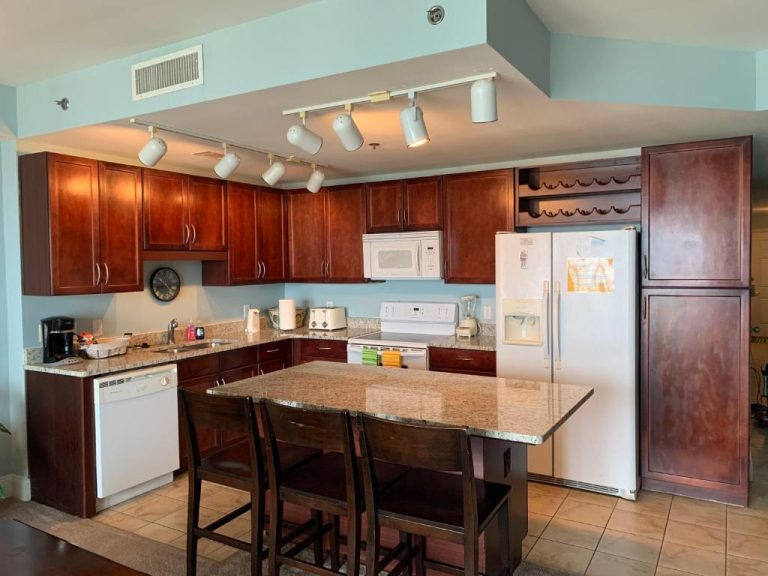 Cocina totalmente equipada con isla central y armarios de madera en apartamento Laketown Wharf 1717