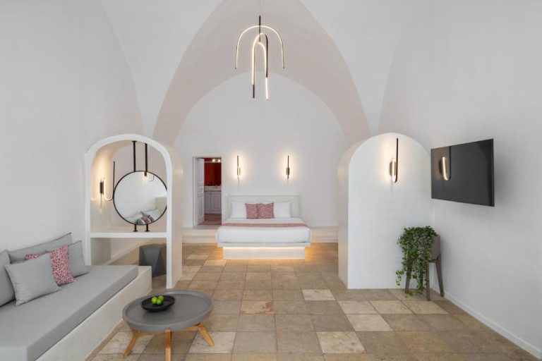 Suite de lujo con techo abovedado blanco, cama flotante y sala de estar en Asha Luxury Suites