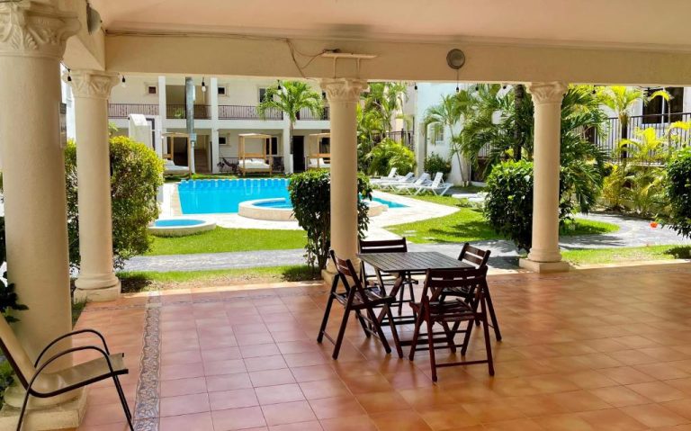Terraza cubierta con mesa y sillas frente a la piscina del hotel Punta Cana Seven Beaches