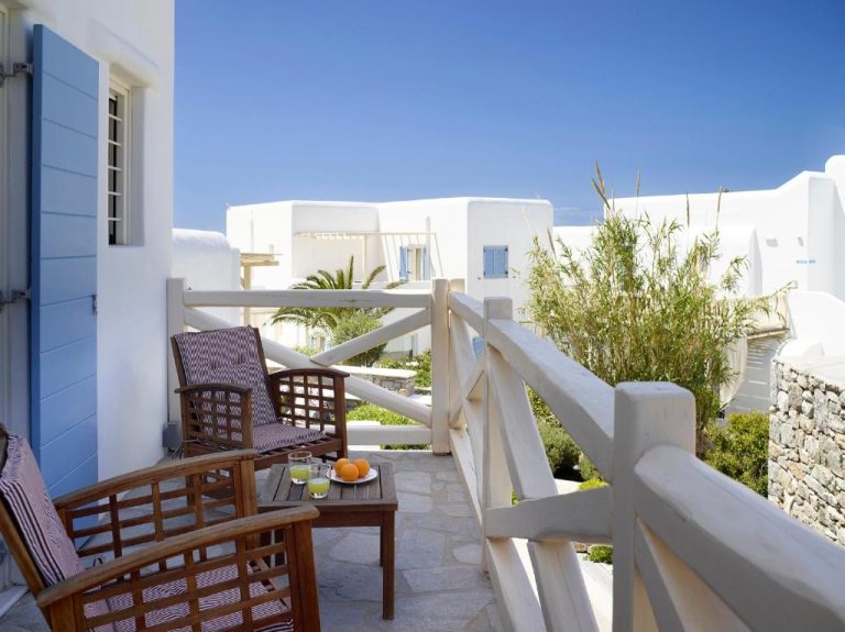 Terraza exterior con sillas de madera y vistas al jardín del Vencia Boutique Hotel en Mykonos