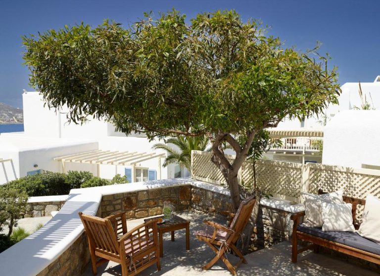 Terraza exterior con mobiliario de madera y árbol en el Vencia Boutique Hotel de Mykonos
