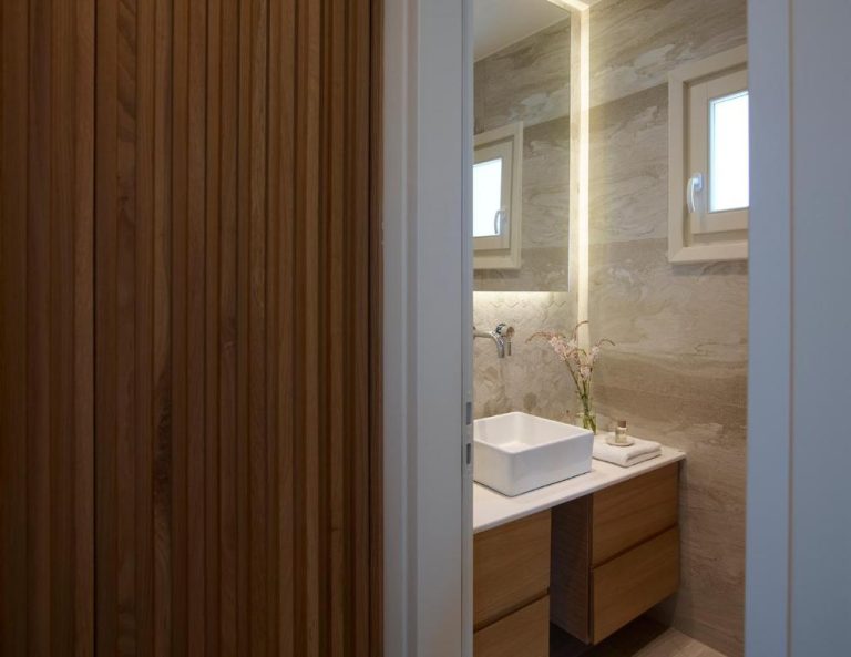 Baño de diseño con lavabo sobre encimera y paredes de mármol en Vencia Boutique Hotel