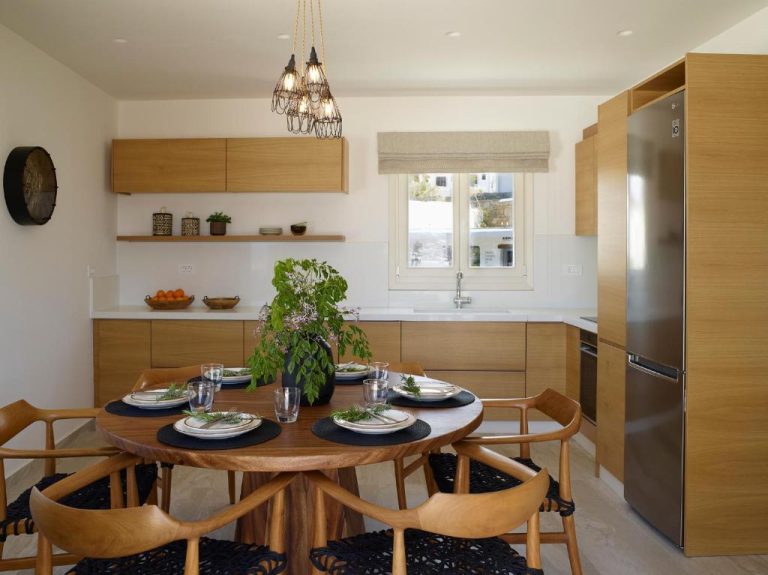 Cocina y comedor con mesa redonda de madera y sillas en el Vencia Boutique Hotel de Mykonos