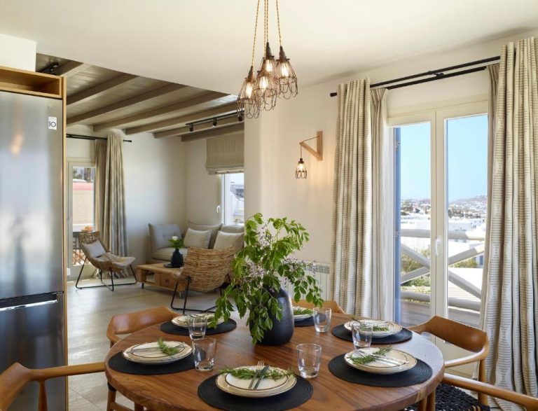 Salón comedor con mesa de madera y vistas panorámicas al exterior en Vencia Boutique Hotel Mykonos