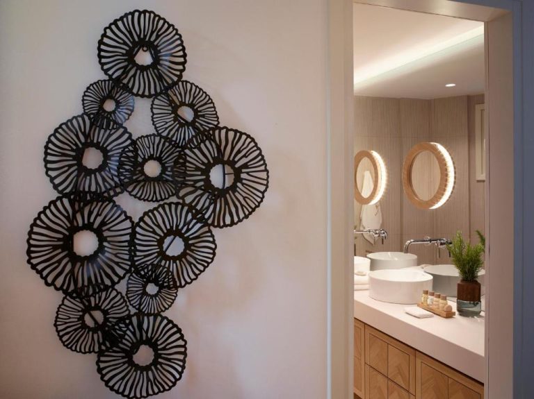 Baño de diseño con lavabos dobles y espejo redondo iluminado en Vencia Boutique Hotel