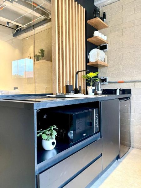 Cocina moderna equipada con microondas, fregadero y estanterías de madera en apartamento Beminimal Parques