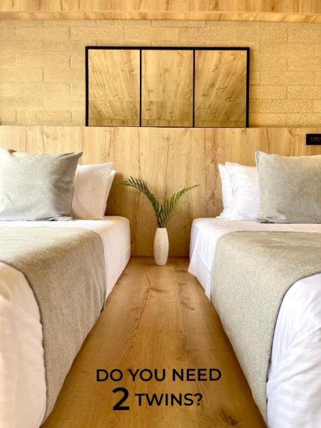 Habitación con dos camas twin en Beminimal Parques, decoración minimalista en madera y ropa de cama blanca