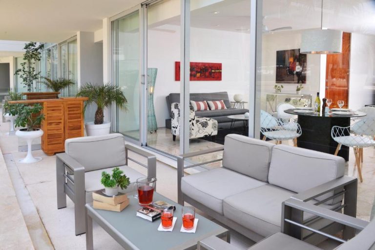 Terraza y salón exterior con sofás blancos y mesa de centro en Magia Beachside Condo