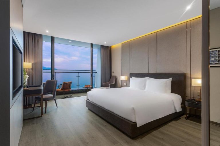 Habitación de lujo con cama king y balcón con vistas al mar en Le Sands Oceanfront Danang Hotel