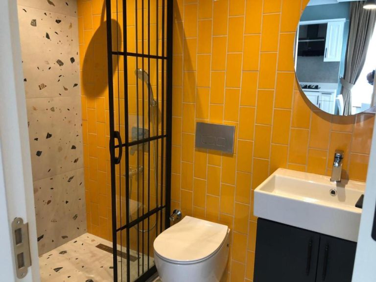 Baño moderno con azulejos amarillos, ducha independiente y lavabo en Juglans Suites