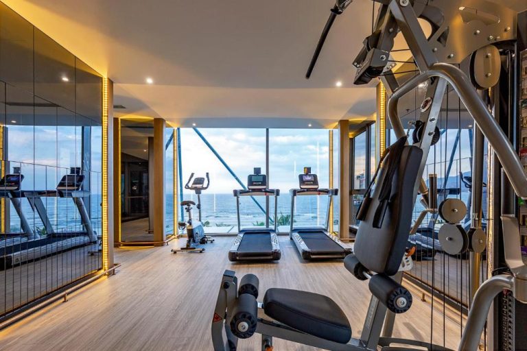 Gimnasio con cintas de correr y vistas panorámicas al mar en Le Sands Oceanfront Danang Hotel