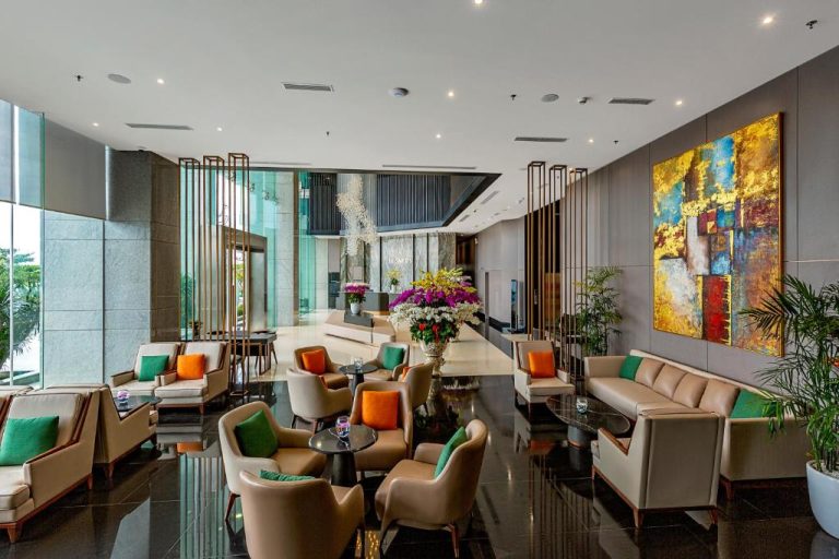 Elegante lobby lounge del Le Sands Oceanfront Danang Hotel con sofás, sillones y arte moderno