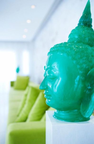 Escultura de Buda turquesa en el lobby del So Nice Beach Resort con sofás verdes al fondo