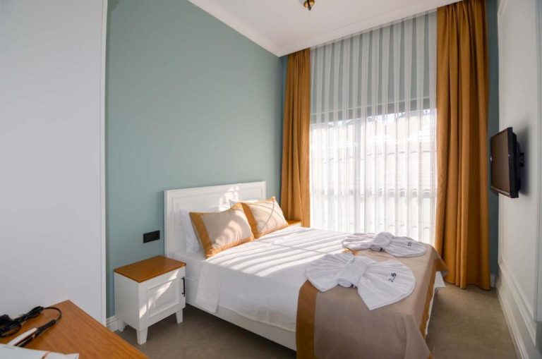 Habitación doble con ventanal luminoso y decoración en tonos dorados del hotel Juglans Suites