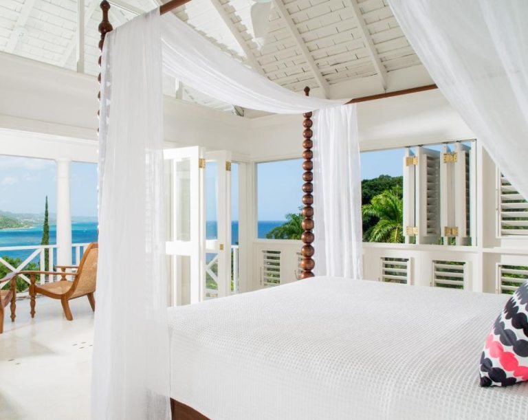 Habitación con cama de dosel y vistas al mar Caribe en Round Hill Hotel & Villas Jamaica