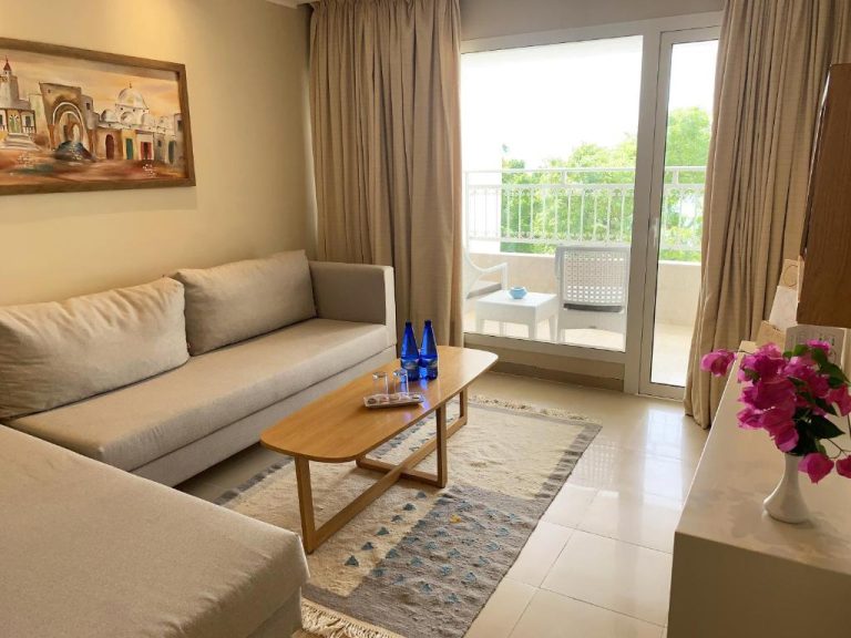 Salón con sofá y terraza con vistas al jardín en Hotel Bel Azur Thalasso & Bungalows