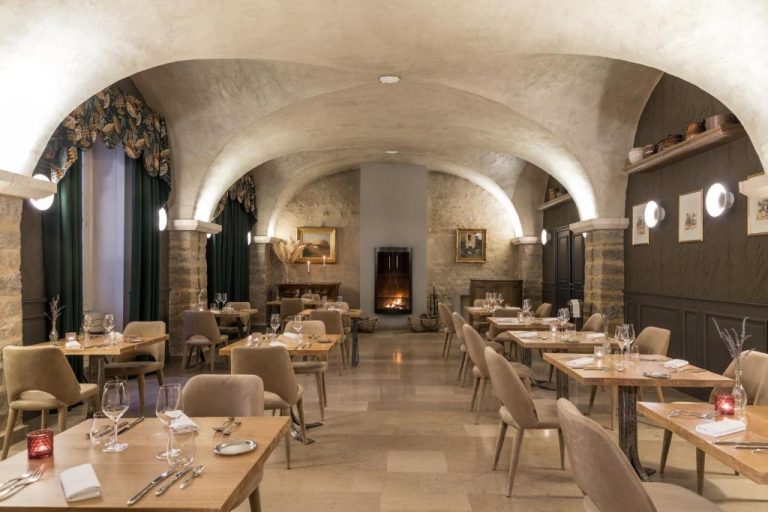 Elegante restaurante con bóvedas de piedra y chimenea encendida en el Château de Saulon