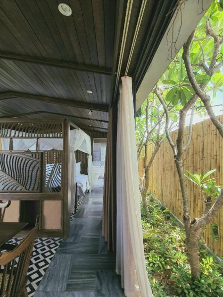 Terraza de madera con cortinas blancas y jardín de bambú en Minh Boutique Hotel
