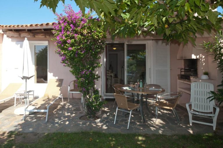 Terraza exterior con mesa y sillas de Résidence Marina Di Santa Giulia con buganvilla en flor