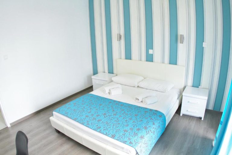 Habitación doble con cama blanca y decoración en azul y blanco en Margarita Napa Apartments