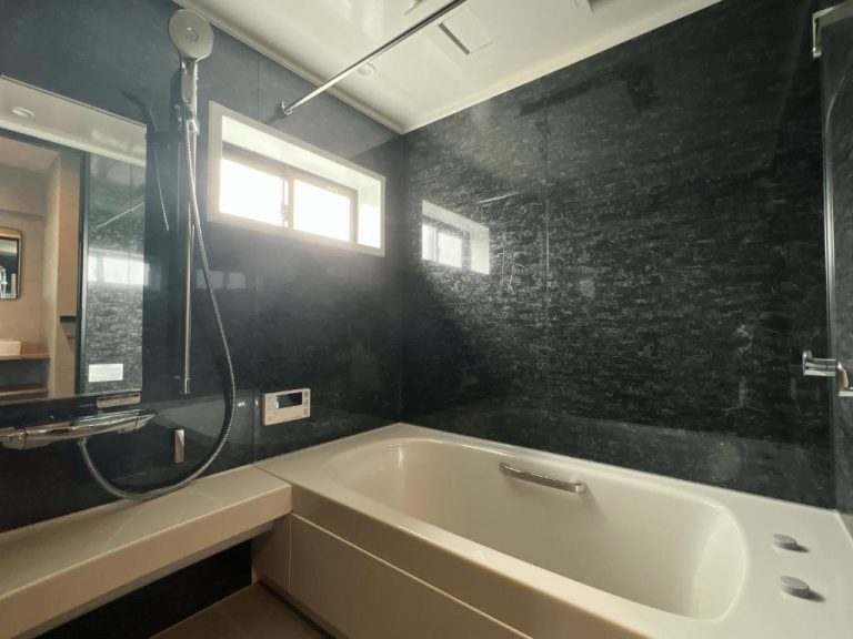 Baño privado con bañera blanca y paredes de piedra negra en el hotel Ulu Tokyo