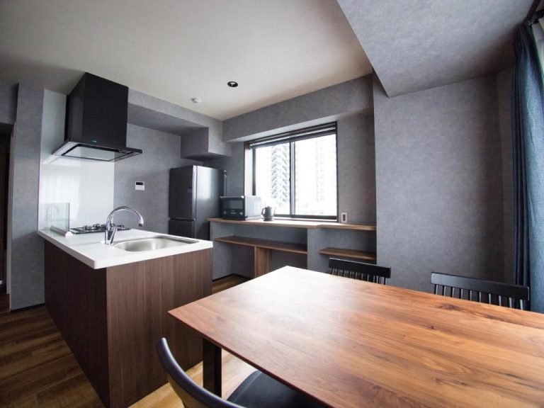 Cocina abierta y comedor con mesa de madera en apartamento moderno del hotel Ulu Tokyo