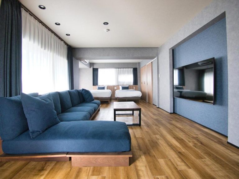 Suite amplia con sofás azules, dos camas y televisión de pantalla plana en hotel Ulu Tokyo