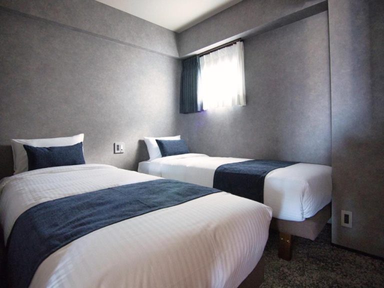 Habitación twin con dos camas individuales y decoración en tonos grises del hotel Ulu Tokyo
