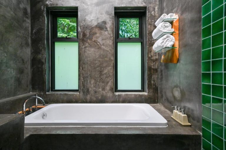 Bañera empotrada con paredes de cemento y ventanas con vistas verdes en Cascade Tara