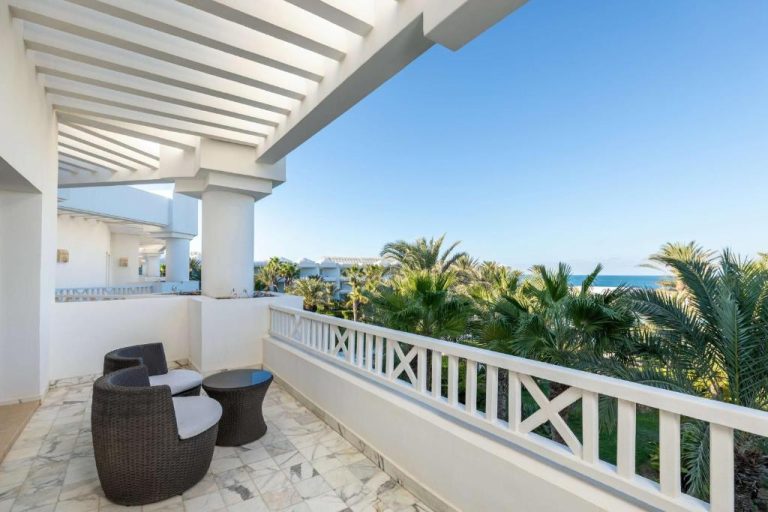 Terraza con mobiliario exterior y vistas al mar y palmeras en Radisson Blu Palace Resort Djerba