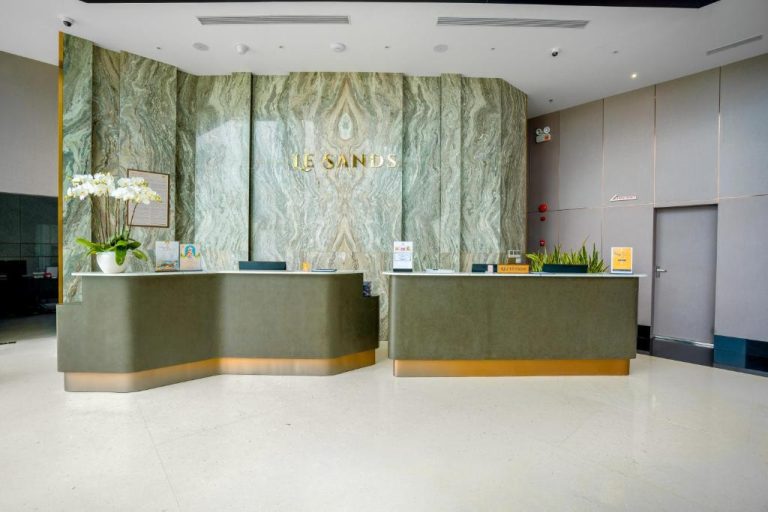 Recepción principal con mármol verde y mostrador dorado del Le Sands Oceanfront Danang Hotel